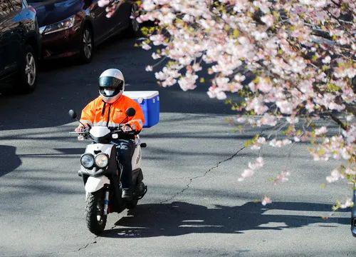 4月1日,在美国纽约,戴口罩的快递员骑车经过一处居民区。新华社记者 王迎 摄