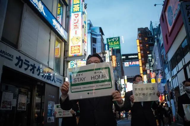 东京市政府工作人员举着牌子劝告人们待在家里。 新华社/西霸