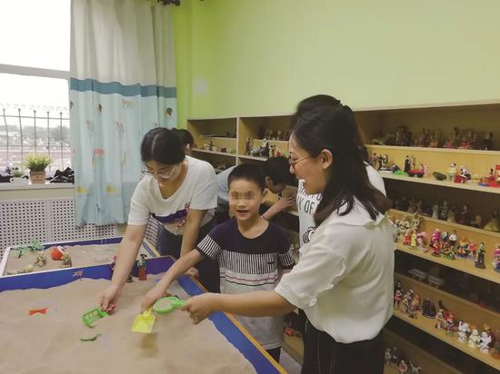 受助儿童在沙盘游戏室内接受工作人员(右)的心理辅导。受访者供图