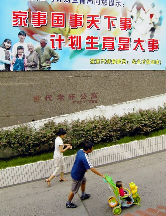 中国实行计划生育政策以来,全国已累计有近1亿独生子女。图为湖北宜昌市街头,一位父亲带着孩子从计划生育广告前经过。